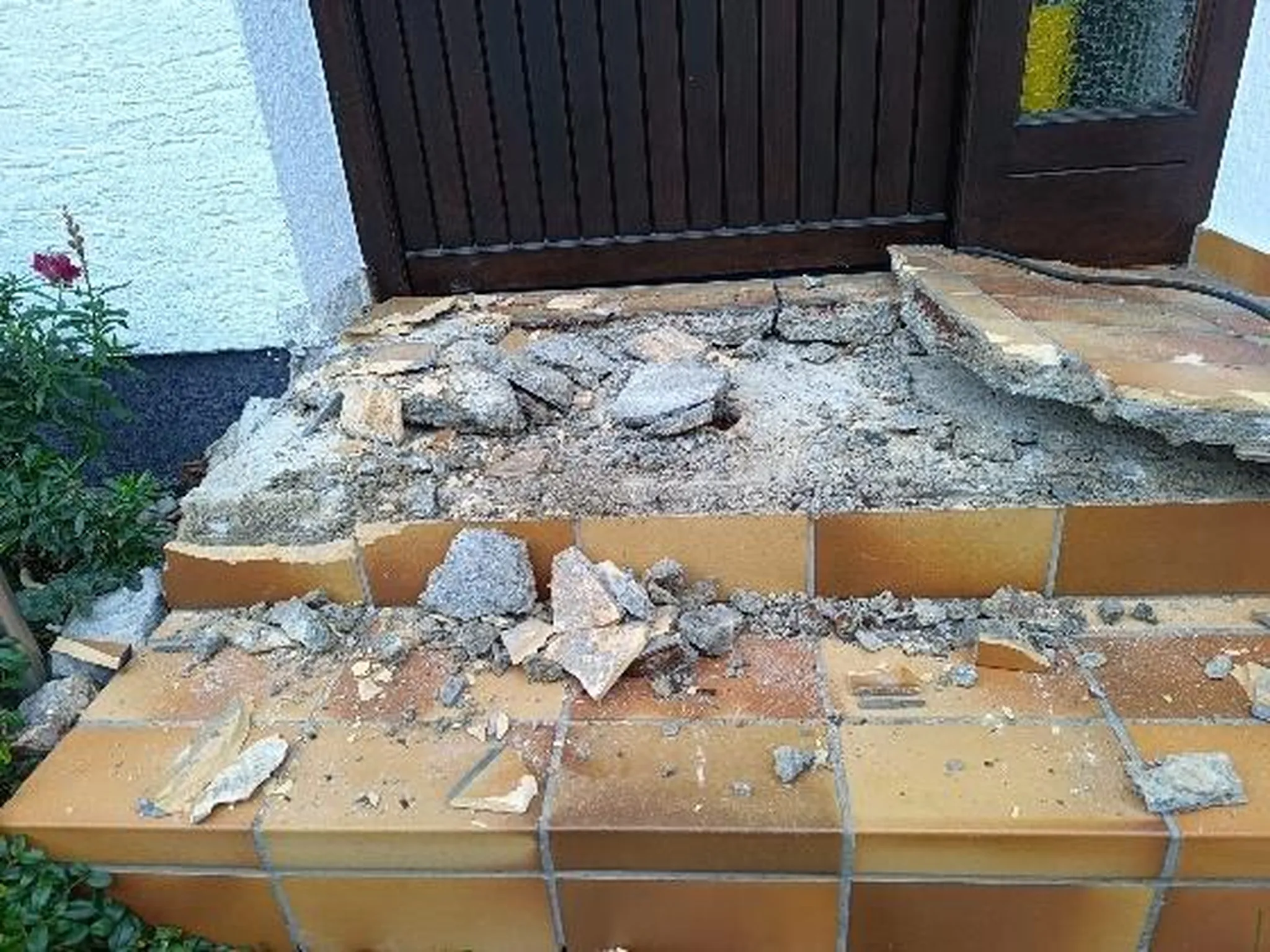 A&S Armbruster & Sieber GmbH - Experten im Bereich Bautenschutz und Bodenbeschichtungen - Kaputte und beschädigte braun geflieste Stufen mit Trümmern vor einer dunkelbraunen Tür