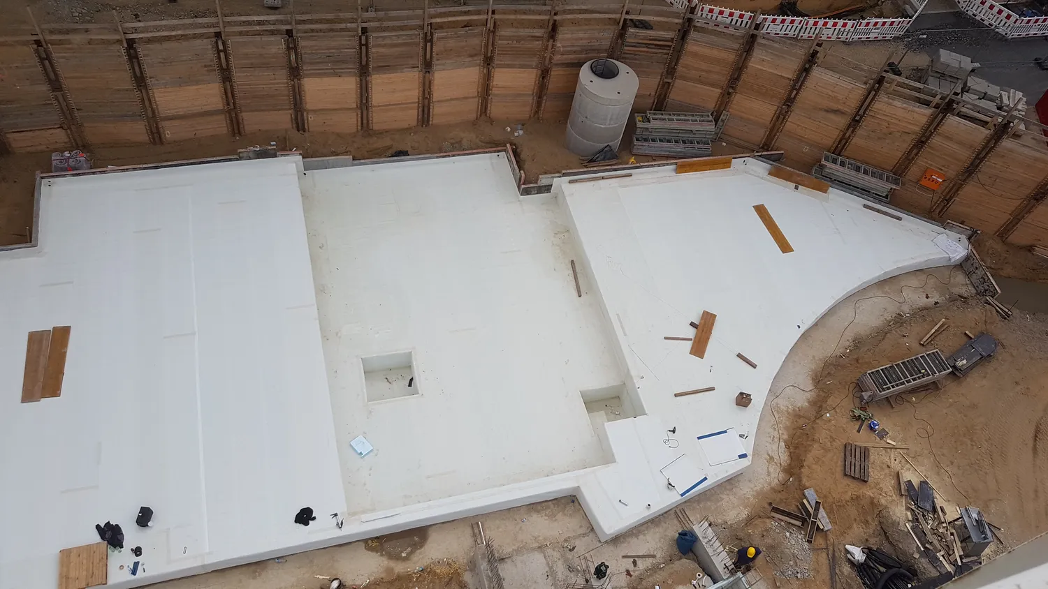 A&S Armbruster & Sieber GmbH - Experten im Bereich Bautenschutz und Bodenbeschichtungen - Luftaufnahme einer Baustelle mit Betonfundamentarbeiten mit Holzbohlen, einer zylindrischen Betonkonstruktion und Arbeitern mit Schutzhelmen