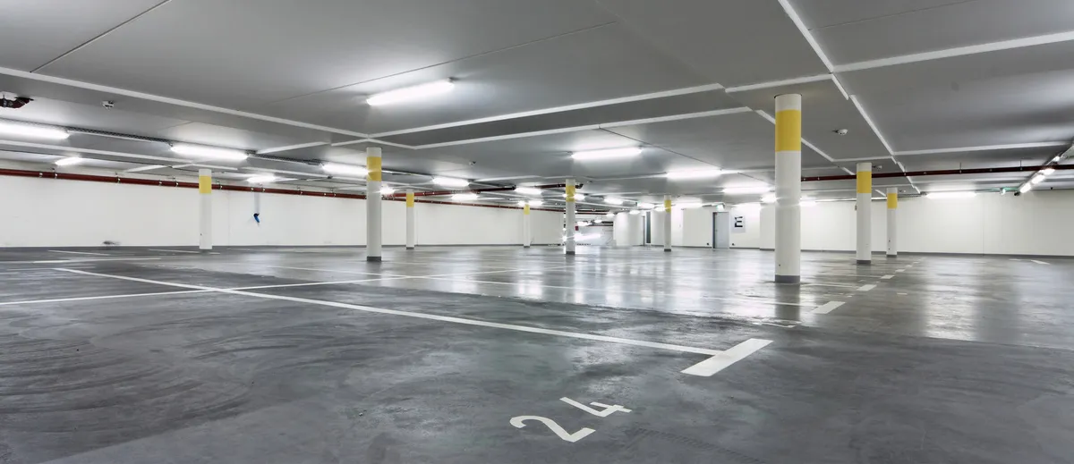 A&S Armbruster & Sieber GmbH - Experten im Bereich Bautenschutz und Bodenbeschichtungen - Leeres Parkhaus mit weißen Wänden, gelb gestreiften Säulen und nummerierten Parkplätzen